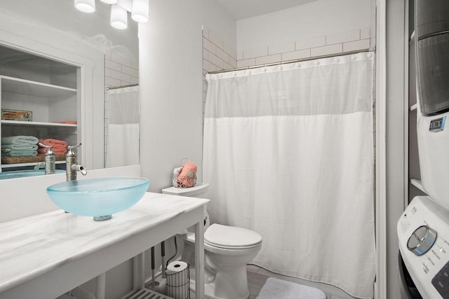 650 Dolphin Prt, Aransas, TX 78373 - bathroom with stacked washing machine and dryer, toilet, vanity, and a shower with curtain
