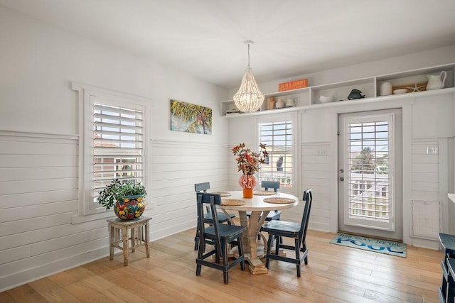 650 Dolphin Prt, Aransas, TX 78373 - dining space with light wood-type flooring, healthy amount of natural light, a chandelier, and wainscoting