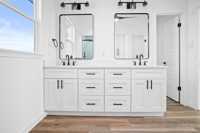 full bath featuring double vanity, a sink, and wood finished floors