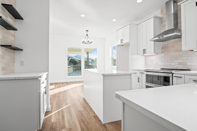 kitchen with white cabinets, light countertops, wall chimney range hood, stainless steel electric range oven, and open shelves