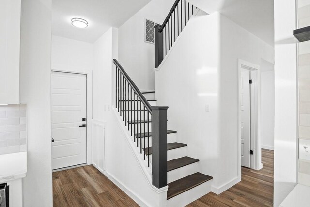 half bathroom featuring lofted ceiling, toilet, vanity, wood finished floors, and baseboards