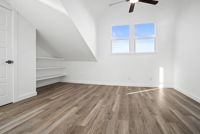 additional living space with vaulted ceiling, a ceiling fan, wood finished floors, and baseboards
