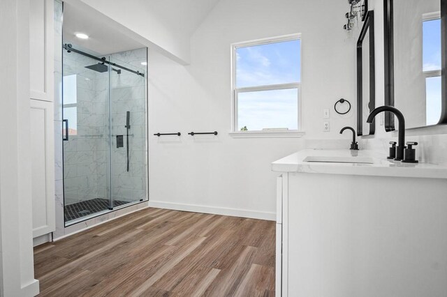 half bathroom with toilet, vaulted ceiling, vanity, wood finished floors, and baseboards