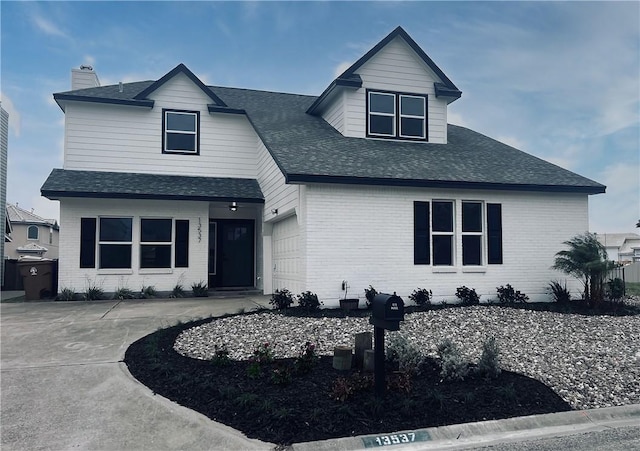 view of front of home with a garage, concrete driveway, brick siding, and a shingled roof