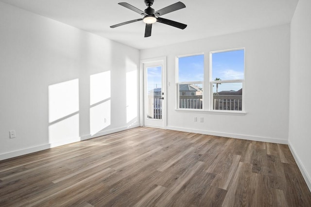 spare room with wood finished floors, a ceiling fan, and baseboards