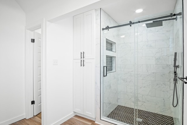 bathroom featuring a stall shower, baseboards, and wood finished floors