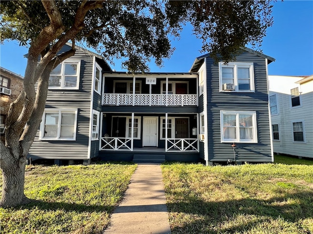 view of front of property with a balcony and a front lawn