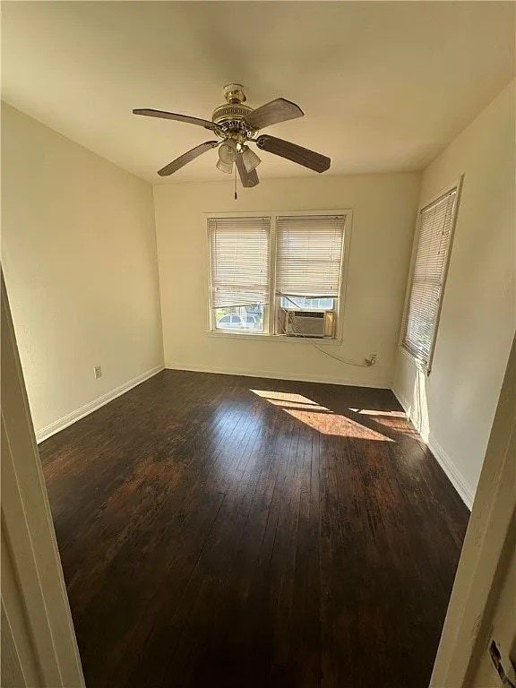 spare room with ceiling fan, cooling unit, and dark wood-type flooring