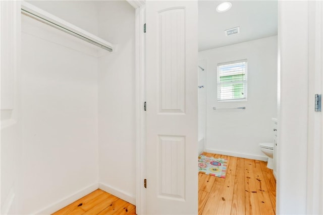 interior space featuring visible vents, baseboards, toilet, and wood finished floors