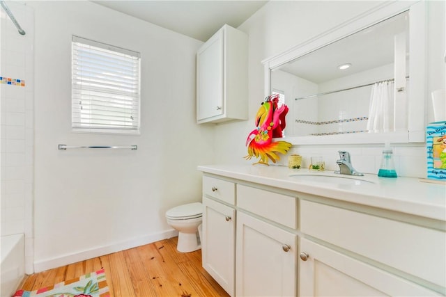 full bath with baseboards, toilet, wood finished floors, and vanity