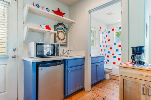 kitchen with visible vents, blue cabinetry, open shelves, stainless steel appliances, and light countertops