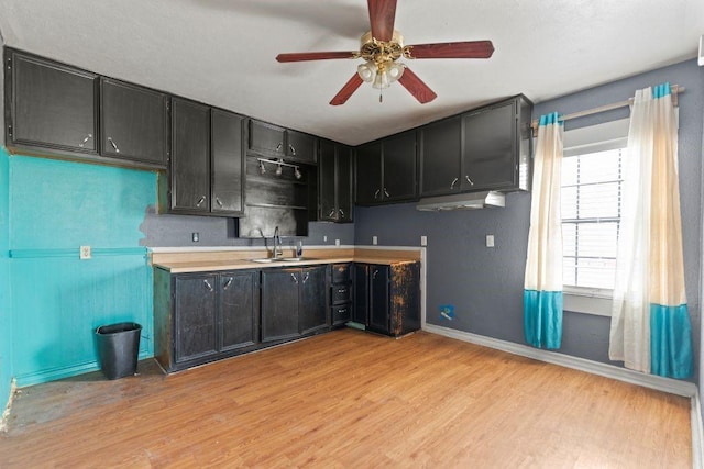 3425 Harold Dr, Corpus Christi, TX 78415 - kitchen featuring light wood-style floors, a ceiling fan, light countertops, and dark cabinetry
