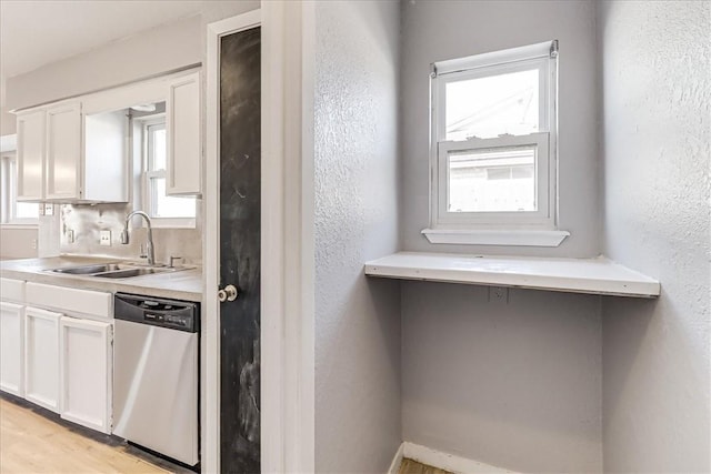 6701 Meadowbreeze Pkwy, Corpus Christi, TX 78414 - kitchen featuring stainless steel dishwasher, a sink, white cabinetry, light countertops, and a textured wall
