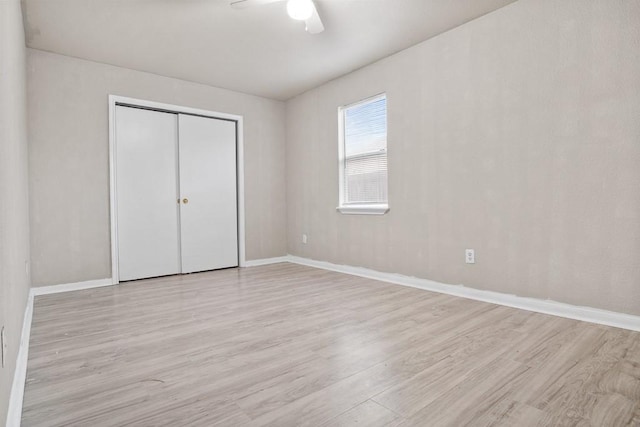 unfurnished bedroom with ceiling fan, light wood-type flooring, and a closet