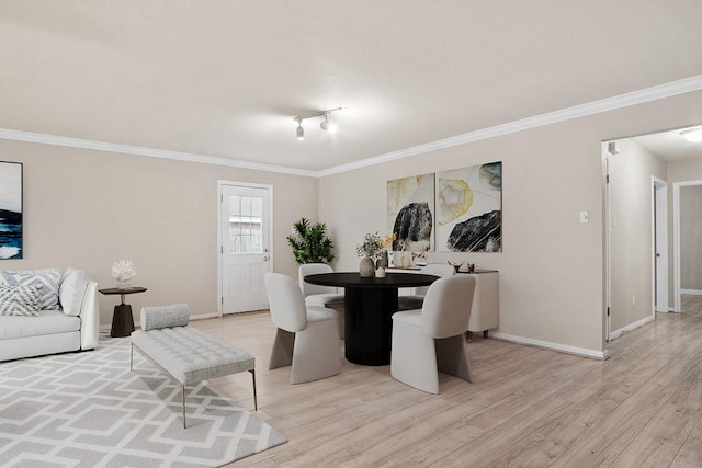 dining space featuring ornamental molding and light hardwood / wood-style flooring