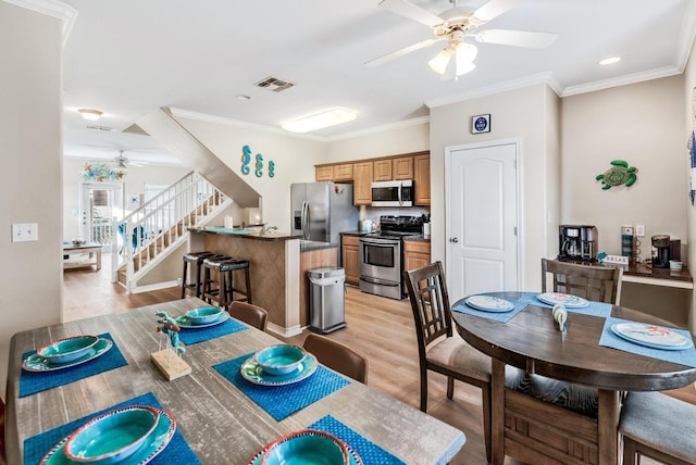 dining space featuring visible vents, a ceiling fan, stairway, crown molding, and light wood-style floors