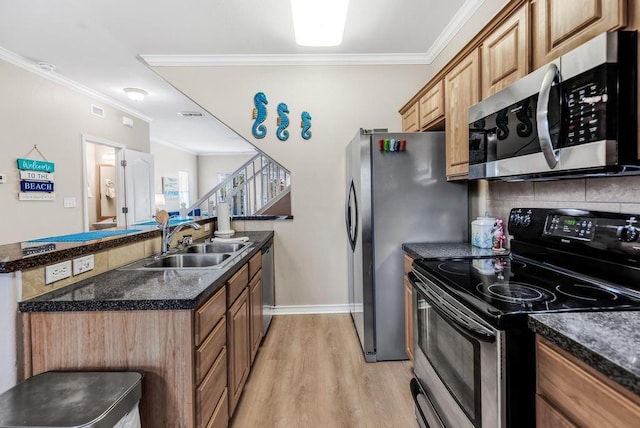 kitchen with light wood finished floors, ornamental molding, a sink, stainless steel appliances, and backsplash