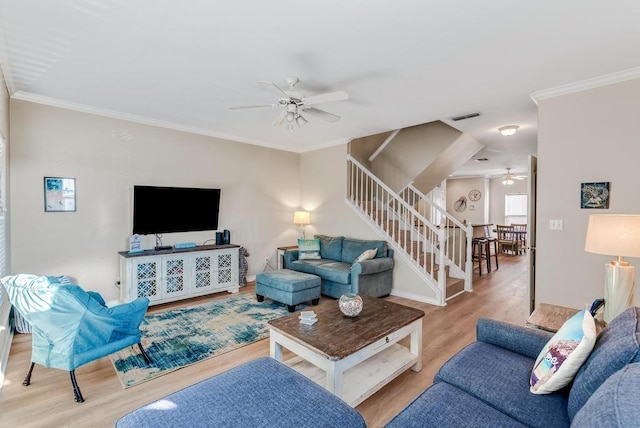 living area featuring stairs, visible vents, wood finished floors, and ornamental molding