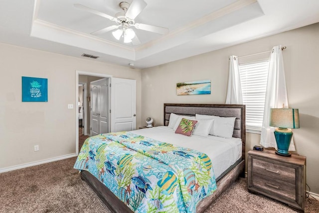 carpeted bedroom featuring a tray ceiling, visible vents, ornamental molding, ceiling fan, and baseboards