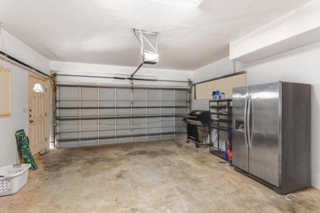 garage with a garage door opener and stainless steel fridge with ice dispenser