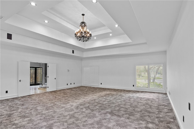 unfurnished living room featuring a chandelier, carpet floors, and a raised ceiling