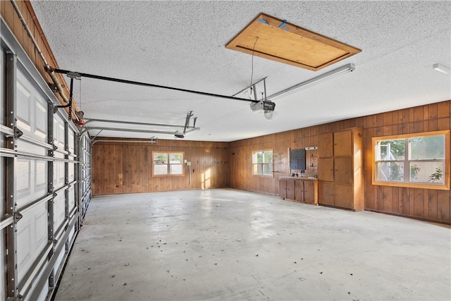 garage featuring a garage door opener and wooden walls