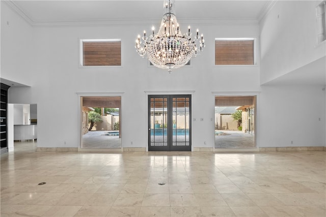 unfurnished living room featuring ornamental molding, french doors, a notable chandelier, and a high ceiling