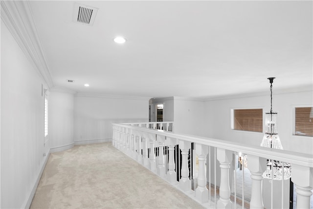 corridor featuring ornamental molding, a wealth of natural light, light colored carpet, and a notable chandelier