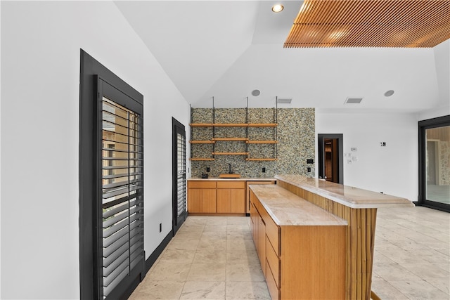 kitchen featuring sink, a breakfast bar, kitchen peninsula, lofted ceiling, and decorative backsplash