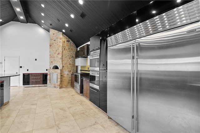 kitchen with stainless steel appliances, a towering ceiling, and wooden ceiling