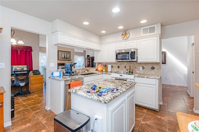 kitchen featuring appliances with stainless steel finishes, tasteful backsplash, visible vents, and white cabinetry