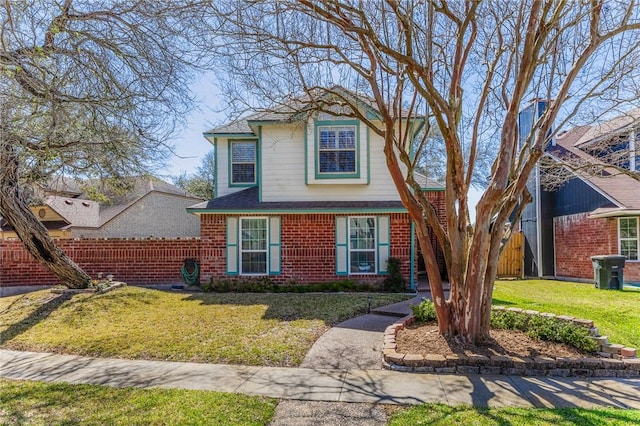 traditional home featuring brick siding, a front yard, and fence