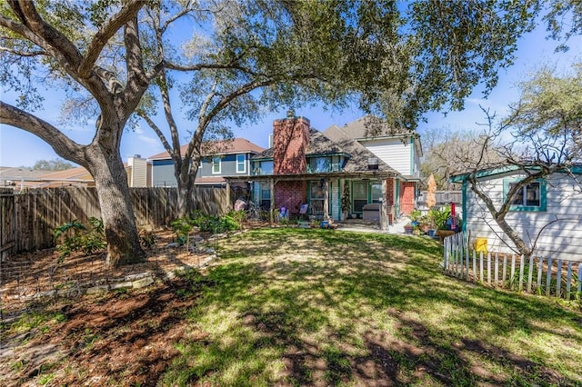 rear view of house with a fenced backyard, a patio, and a yard