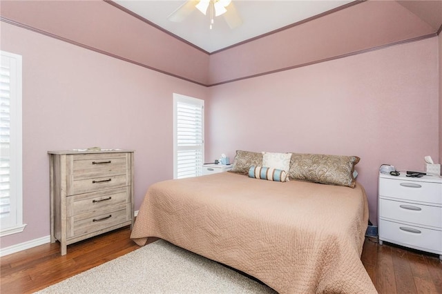 bedroom featuring ceiling fan, dark wood-type flooring, multiple windows, and ornamental molding