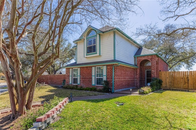 traditional-style home featuring fence, a front lawn, and brick siding