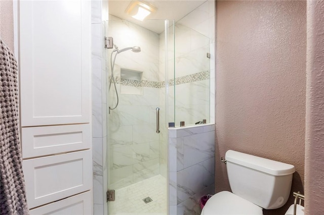 bathroom featuring toilet, a textured wall, and a marble finish shower