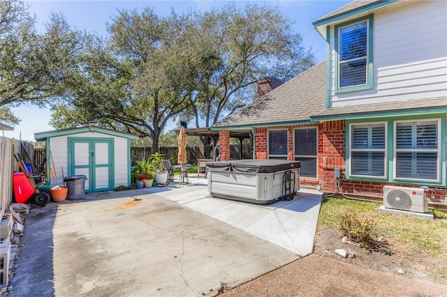 view of patio with ac unit, an outbuilding, a hot tub, a shed, and a fenced backyard