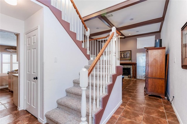 stairs with ornamental molding, visible vents, a fireplace, and baseboards