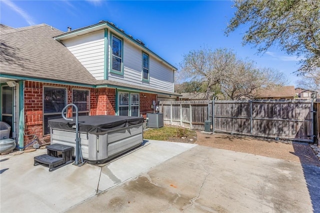 back of house featuring brick siding, a patio area, cooling unit, and a hot tub