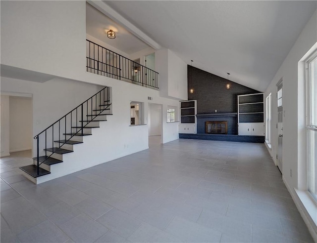 4802 Eider Dr, Corpus Christi, TX 78413 - unfurnished living room with high vaulted ceiling, a brick fireplace, and stairs