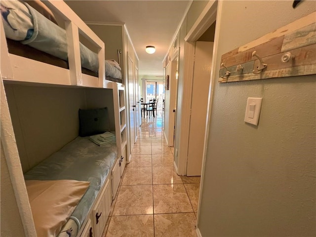 corridor featuring light tile patterned floors and crown molding