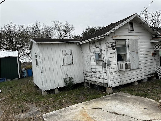 view of side of home featuring cooling unit and a shed