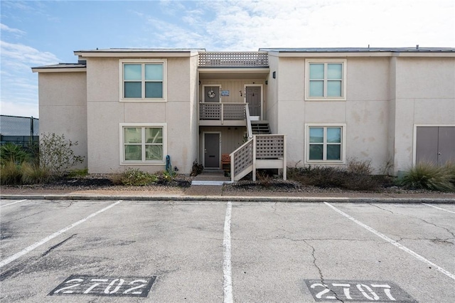 view of property with uncovered parking and stairway