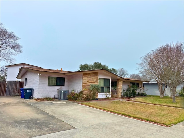 ranch-style home featuring cooling unit and a front lawn