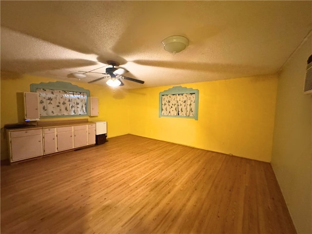 unfurnished living room with ceiling fan, light hardwood / wood-style floors, and a textured ceiling