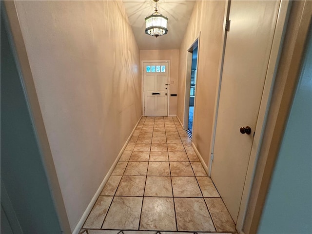 hall with an inviting chandelier and light tile patterned floors