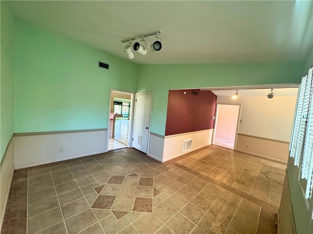 unfurnished room featuring track lighting and lofted ceiling