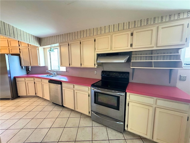 kitchen with sink, light tile patterned floors, stainless steel appliances, and cream cabinetry