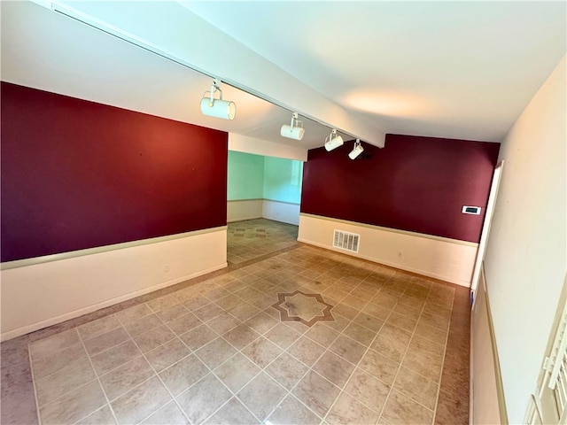 empty room featuring rail lighting and lofted ceiling