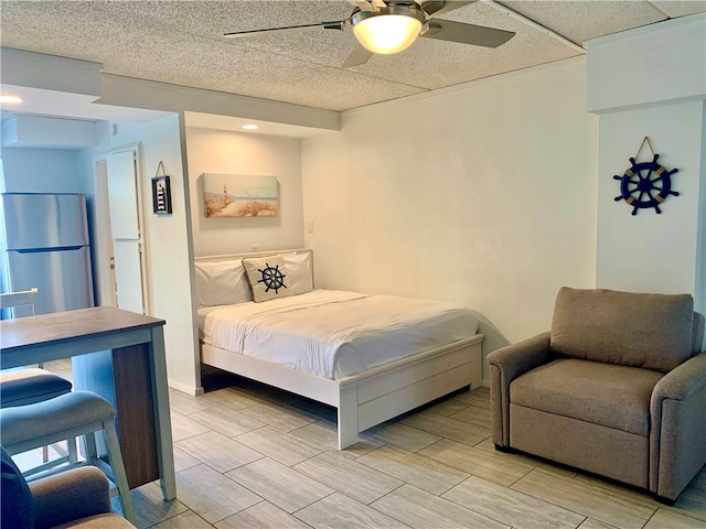 bedroom featuring light hardwood / wood-style floors, ceiling fan, and stainless steel fridge